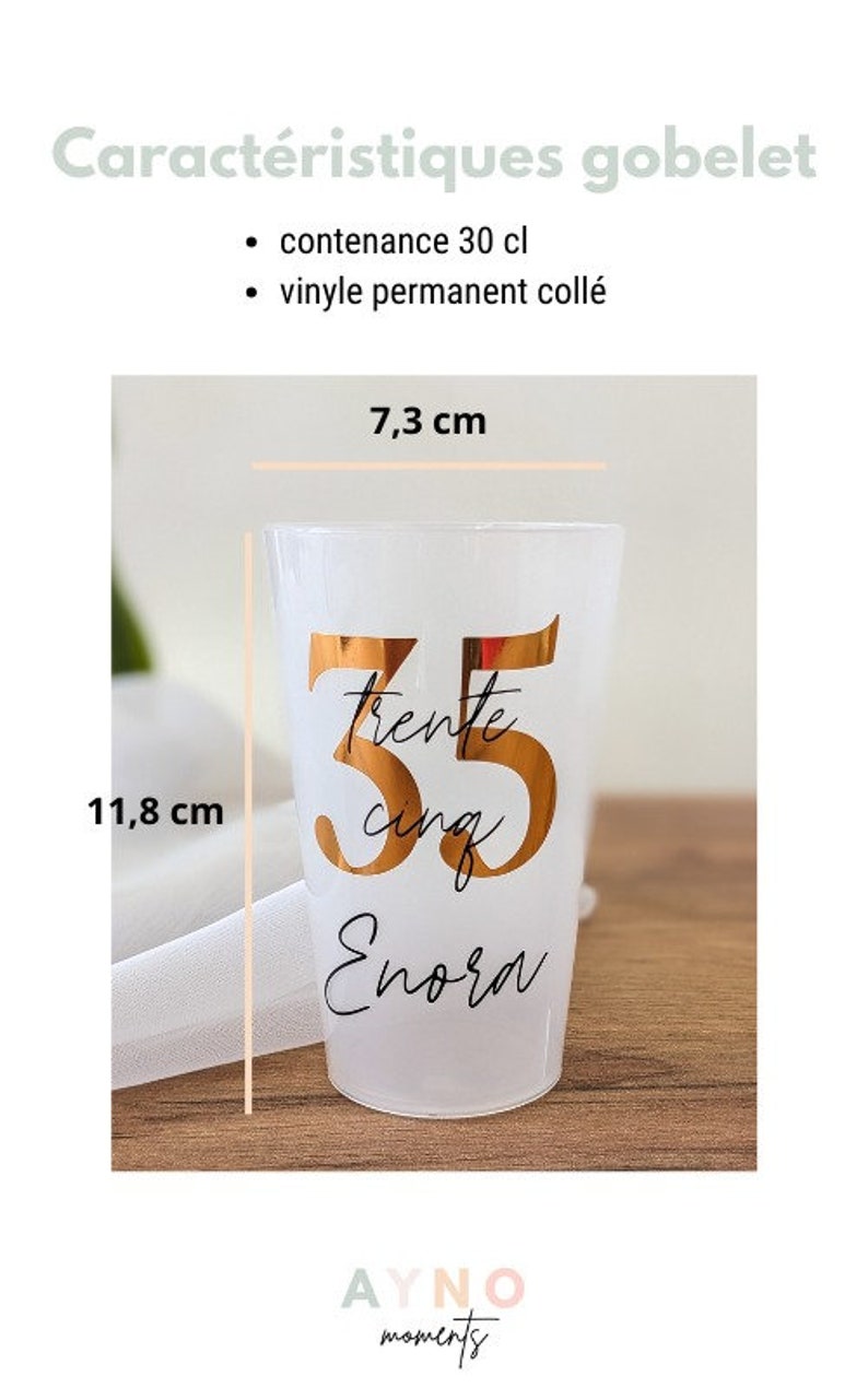 May include: A white plastic goblet with a gold vinyl design that says "trente cinq Enora" and the number 35. The goblet is 7.3 cm wide and 11.8 cm tall.