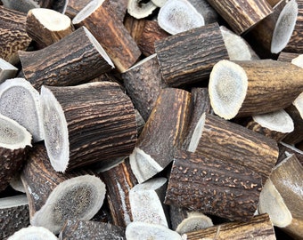 May include: A close-up of a box filled with various sizes of natural brown antler dog chews.