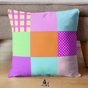 以下が含まれることがあります： パッチワークデザインの正方形クッション。ピンク、黄色、オレンジ、緑、青の色合いの9つのカラフルな正方形が特徴です。水玉模様やチェック柄などのパターンもあります。