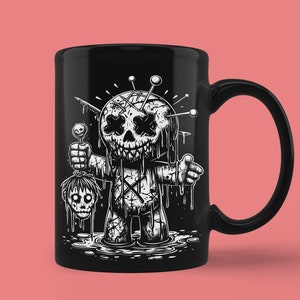 May include: Black ceramic mug with a white illustration of a stitched-up doll with a dripping face and a severed head in its hand. The doll is holding a lollipop in its other hand.