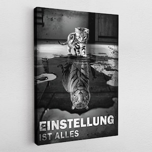 Puede incluir: Foto en blanco y negro de un pequeño gatito mirando su reflejo en un charco de agua. El reflejo aparece como un gran tigre. El texto "EINSTELLUNG IST ALLES" está impreso debajo de la imagen.