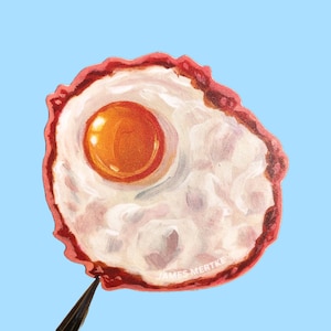 May include: A hand-painted illustration of a fried egg with a bright orange yolk and a white, slightly textured egg white. The egg is surrounded by a red border.