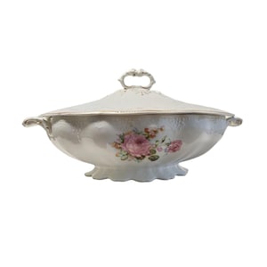 Könnte beinhalten: Eine weiße Porzellanservierschale mit Deckel. Die Schale hat ein florales Design mit rosa Rosen und grünen Blättern. Der Deckel hat einen goldfarbenen Griff.