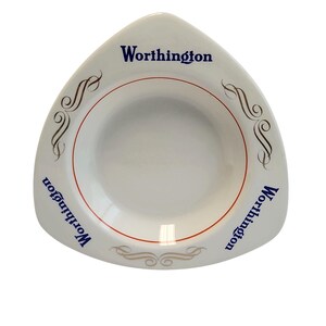 Può includere: Una ciotola triangolare in ceramica bianca con la parola Worthington stampata in blu su tre lati. La ciotola è decorata con sottili linee circolari rosse attorno al bacino centrale e decorazioni dorate a volute tra i testi.