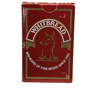 Può includere: Un mazzo di carte rettangolare in una scatola rossa con bordi dorati. Il fronte presenta il logo Whitbread, un cervo stilizzato, e il testo: WHITBREAD BREWERS OF FINE BEERS SINCE 1742. La linguetta superiore mostra la parola whist in bianco.