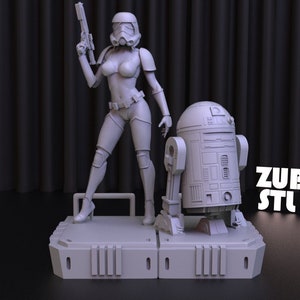 May include: A white 3D printed figurine of a female Stormtrooper wearing a bikini and holding a blaster, standing next to a white 3D printed figurine of R2-D2. The figurines are on a white 3D printed base with the text "ZUBARH STL ART".