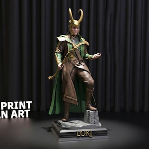 May include: A detailed 3D-printed statue of Loki, featuring a green and gold helmet with horns, a green cape, and brown attire. The statue stands on a base with the name "LOKI" and the text "3DPRINT FAN ART".
