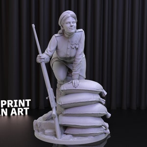 Puede incluir: Una figura impresa en 3D de una mujer con uniforme militar, sosteniendo un rifle y de pie sobre una pila de sacos de arena. La figura está pintada de color gris claro.