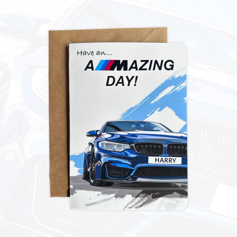 May include: A greetings card featuring a blue sports car illustration with the text Have an... A-MAZING DAY! and a personalised number plate reading HARRY. The card is positioned in front of a brown paper envelope on a light background.