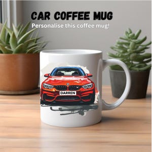 Può includere: Tazza da caffè in ceramica bianca con un'illustrazione di un'auto rossa. L'auto ha una targa nera che recita "DARREN".