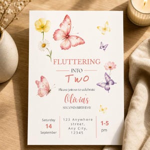 Op de afbeelding: Een witte verjaardagsuitnodigingskaart met aquarelillustraties van roze, paarse en gele vlinders en bloemen. De tekst luidt: FLUTTERING INTO Two, Please join us to celebrate Olivia's SECOND BIRTHDAY, Saturday 14 September, 123 Anywhere street, Any City, 12345, 1-5 pm.