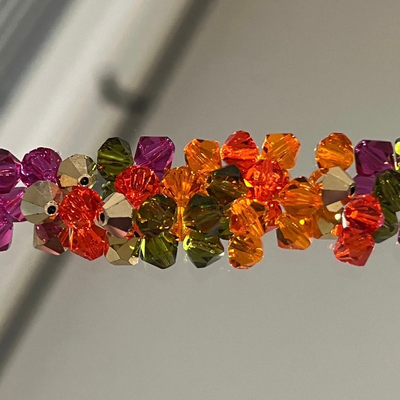 May include: A mix of orange, green, and purple glass beads. The beads are faceted and have a shiny finish.