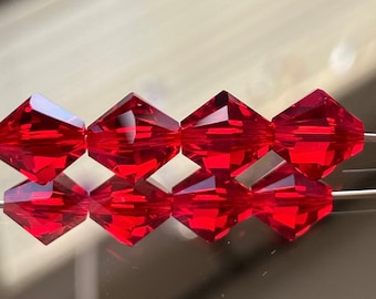 May include: Six red crystal beads with a faceted diamond shape. The beads are strung on a clear thread.