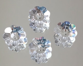 May include: Four clear crystal flower-shaped beads with a hole in the center. The beads are faceted and have a slight iridescent shimmer.