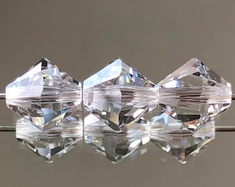 May include: Three clear faceted glass beads with a diamond shape. The beads are strung together on a clear thread.