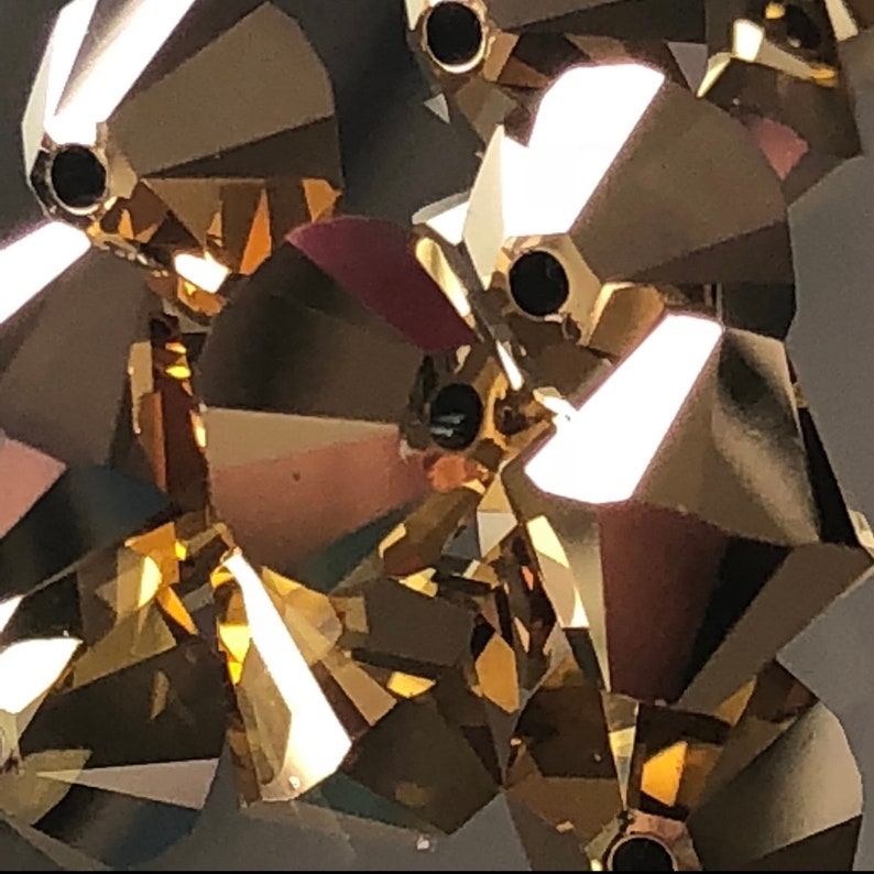 May include: Close-up of gold-toned crystal beads with a faceted design. The beads have a shiny, reflective surface.