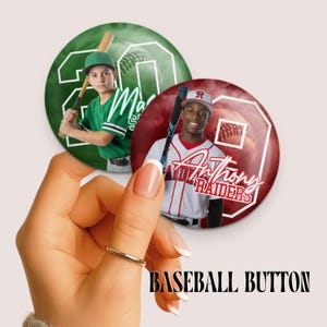 May include: Two circular pin-back buttons featuring baseball players. One green button shows a player in a green jersey holding a bat with the number 20. The other red button shows a player in a white jersey holding a bat with the name Anthony Raiders.