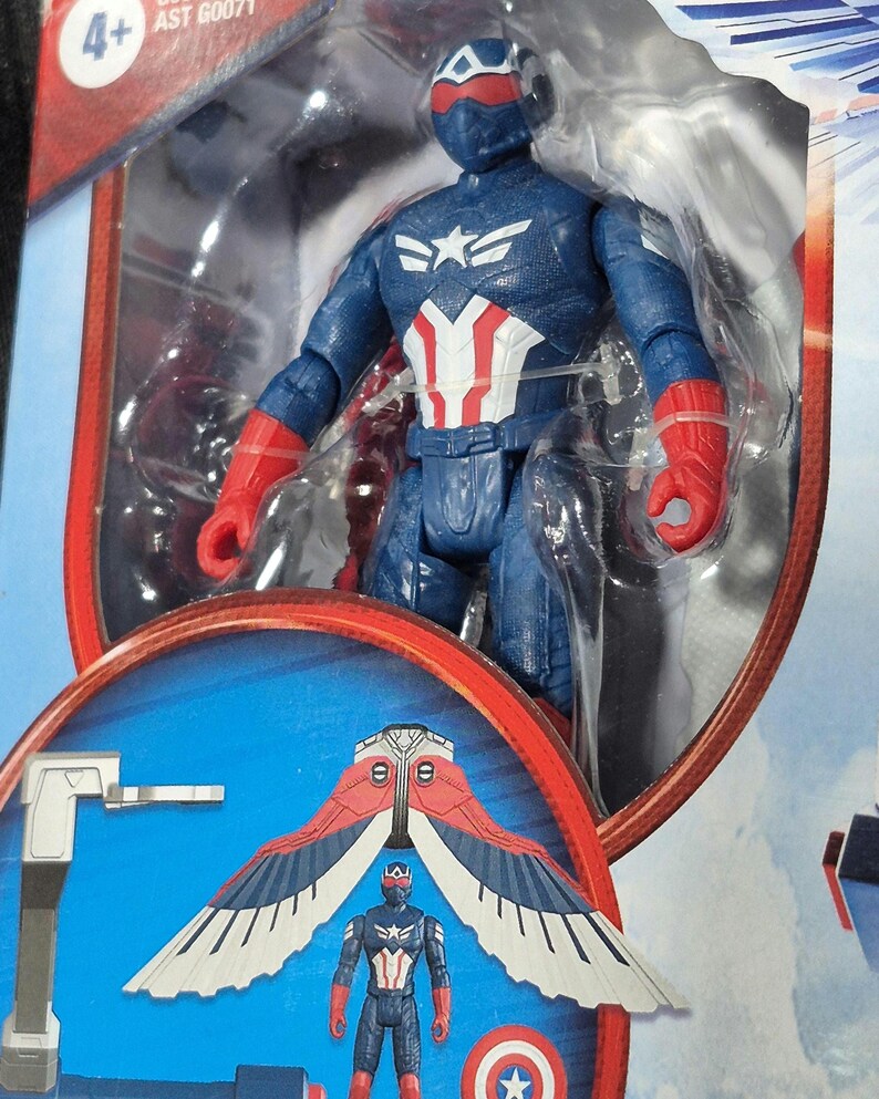 May include: A Captain America action figure in blue, red, and white tactical gear with a matching helmet and red gloves, encased in clear plastic packaging. The packaging features an illustration of the figure with large, detachable red and white wings.