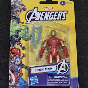 Puede incluir: Una figura de acci&oacute;n de Iron Man de Marvel Avengers en su empaque bl&iacute;ster original amarillo y azul. La figura es roja y dorada con una pieza azul en el pecho y un accesorio azul transl&uacute;cido. La tarjeta presenta ilustraciones de Thor, Captain Marvel, Hulk, Black Panther, Iron Man y Captain America.