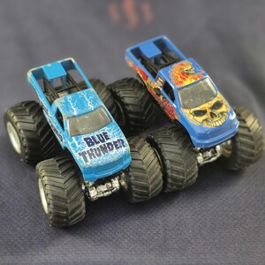 Pair of Hot Wheels Monster Jam Trucks including Blue Thunder & Instigator in good preowned condition.