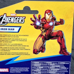 Puede incluir: Una tarjeta de respaldo para figura de acci&oacute;n Marvel Avengers amarilla con Iron Man en un traje rojo y dorado. La tarjeta muestra el logo de Avengers, el texto Iron Man, texto descriptivo en varios idiomas y una etiqueta de advertencia.