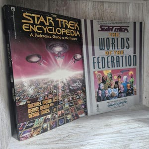 May include: Two vintage Star Trek books. The Star Trek Encyclopedia, a reference guide to the future, features a space scene. The Worlds of the Federation book cover displays various alien characters. Both books are on a wooden surface.