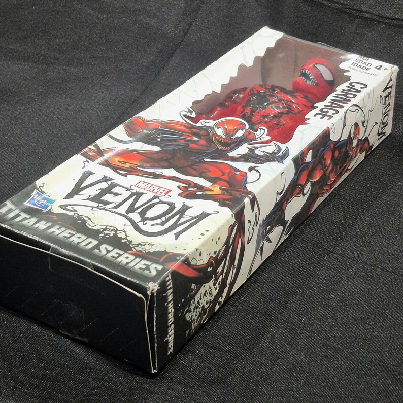 May include: A Marvel Venom Titan Hero Series Carnage action figure inside a rectangular cardboard box with a clear plastic window. The packaging features red and black character illustrations, the name Carnage, and the Hasbro logo on the front.