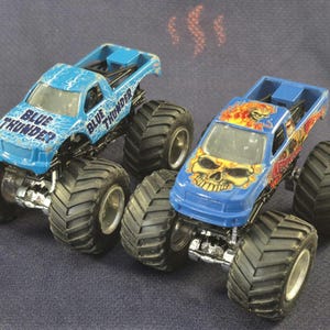 Pair of Hot Wheels Monster Jam Trucks including Blue Thunder & Instigator in good preowned condition.