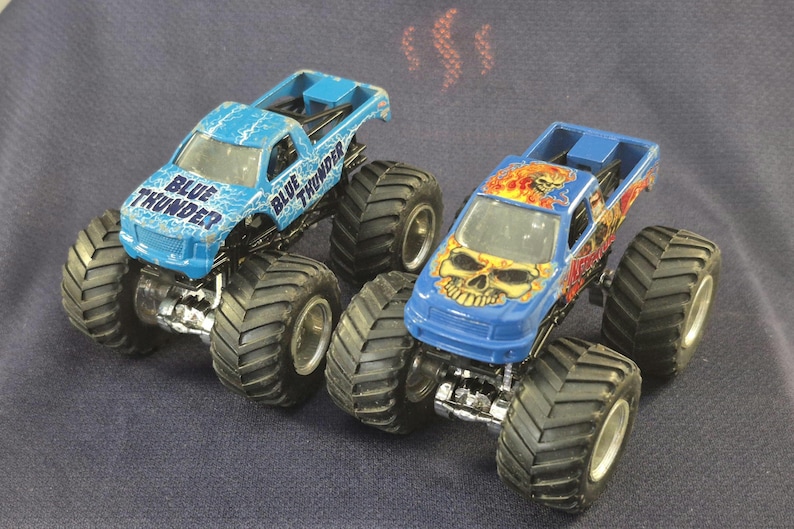Pair of Hot Wheels Monster Jam Trucks including Blue Thunder & Instigator in good preowned condition.