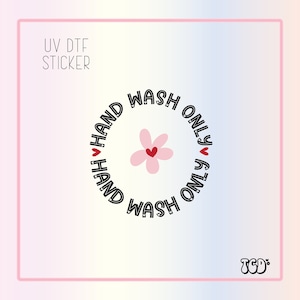 May include: A black and white sticker with a pink flower and the text "HAND WASH ONLY" repeated twice in a circle. The sticker is labeled "UV DTF STICKER".