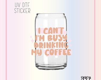 May include: A clear glass can with a pink and brown sticker that says "I can't I'm busy drinking my coffee".