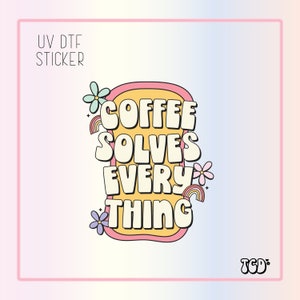 May include: A UV DTF sticker with the text "COFFEE SOLVES EVERYTHING" in a retro font. The design includes flowers and rainbows, set against a yellow and pink background. The sticker has a pink border and the TCD logo.
