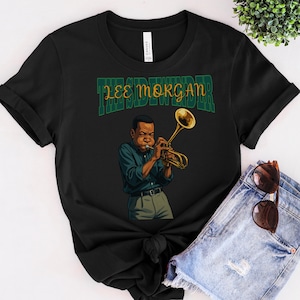 Può includere: Maglietta nera con una grafica verde e gialla di un uomo che suona la tromba. La grafica include il testo "The Sidewinder Lee Morgan".