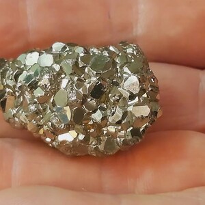 May include: A cluster of pyrite crystals, also known as fool's gold, with a metallic gold colour and a rough, textured surface.