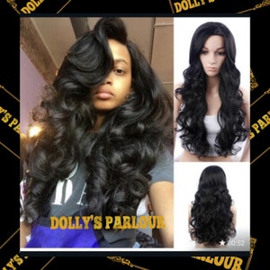 May include: A black long wavy wig with a lace front. The wig is styled with loose curls and is worn by a person with dark skin.