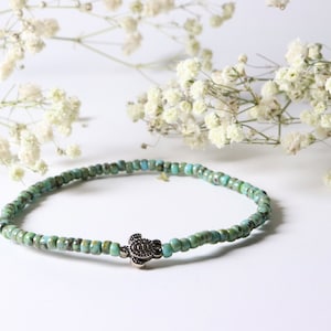 Peut inclure: Un bracelet en perles turquoise avec un pendentif en forme de tortue argentée.