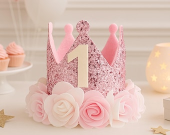 May include: Pink glitter crown with a white felt number one and a pink felt base decorated with white and pink felt roses.