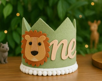 May include: A green felt crown featuring a lion applique and the word "one". The lion is brown and tan with black eyes. The crown has a white pom-pom trim. Ideal for a first birthday celebration, it's a charming accessory.