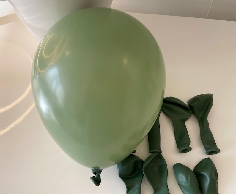 May include: A large sage green balloon with a glossy finish, surrounded by smaller dark green balloons.