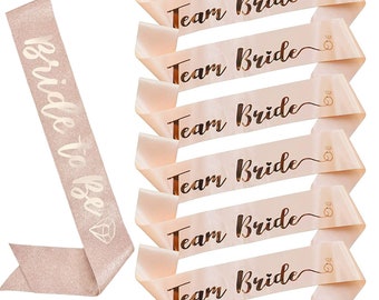 May include: Six pink satin sashes with gold glitter lettering that reads "Team Bride". One pink satin sash with gold glitter lettering that reads "Bride to Be".