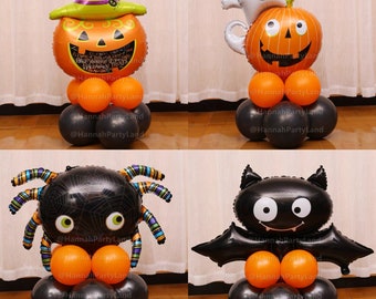 May include: Four Halloween balloon centerpieces. A pumpkin with a witch's hat, a pumpkin with a ghost, a spider, and a bat. Each centerpiece is made of orange and black balloons.