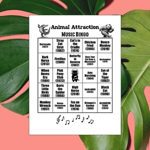 K&ouml;nnte beinhalten: Eine wei&szlig;e Bingo-Karte mit dem Titel "Animal Attraction Music Bingo" mit Tierillustrationen und Songtiteln. Die Karte zeigt eine Vielzahl von Tieren und Songtiteln, darunter "Barracuda" und "Monkey Wrench". Die Karte ist von gr&uuml;nen Bl&auml;ttern umgeben.