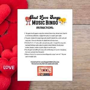 May include: A white sheet of paper with the text "Best Love Songs Music Bingo" and instructions. The image includes a red cassette tape graphic with the words "Love Songs". Red heart-shaped decorations are in the background.