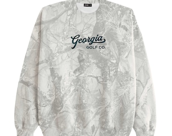 Könnte beinhalten: Ein weißes und graues Sweatshirt mit Camouflage-Muster. Der Text "Georgia GOLF CO." ist in dunkelgrüner Schrift gehalten. Das langärmlige Sweatshirt mit Rundhalsausschnitt hat eine klassische Passform und ein Etikett am Halsausschnitt.