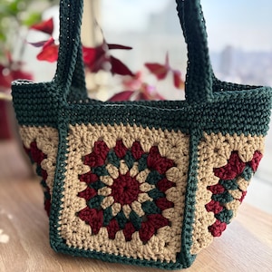 May include: A green, beige, and burgundy crocheted tote bag with a square design. The bag has two straps and is made with a granny square pattern.