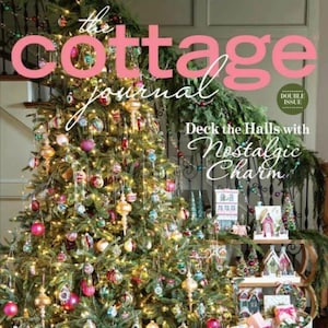 以下が含まれることがあります： カラフルなオーナメント、ライト、ガーランドで飾られたクリスマスツリー。ツリーは、ラッピングされたプレゼントと白いそりで囲まれています。ツリーの上に「Deck the Halls with Nostalgic Charm」という文字が表示されています。