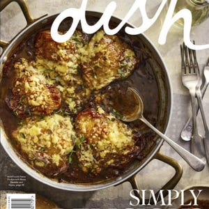 May include: A magazine cover featuring a close-up of a dish of French onion chicken with sharp cheddar and thyme. The dish is in a copper-colored pan with handles. The magazine title "dish" is in white, with the words "Simply Delicious" below.