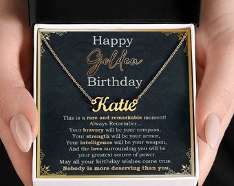 May include: A gold necklace with a nameplate that says "Katie" in a gold cursive font. The necklace is in a black box with a white background and the text "Happy Golden Birthday" and a message about bravery, strength, intelligence, and love.