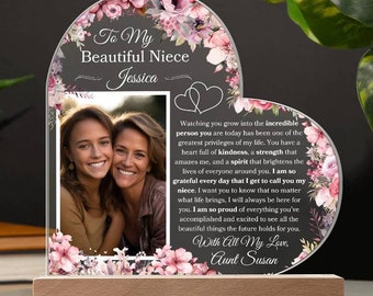 Puede incluir: Un marco de fotos acrílico en forma de corazón con base de madera. El marco presenta una foto de dos mujeres sonriendo, adornos florales y el texto "To My Beautiful Niece Jessica". El marco incluye un mensaje de "Aunt Susan".