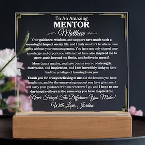 May include: A clear acrylic plaque with a gold border and a message to an amazing mentor named Matthew. The message expresses gratitude for the mentor's guidance, wisdom, and support. The plaque is on a wooden base.